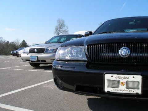 2001 Ford Crown Victoria - Two Mercury Grand Marquis sedans parked in a lot under a clear blue sky.