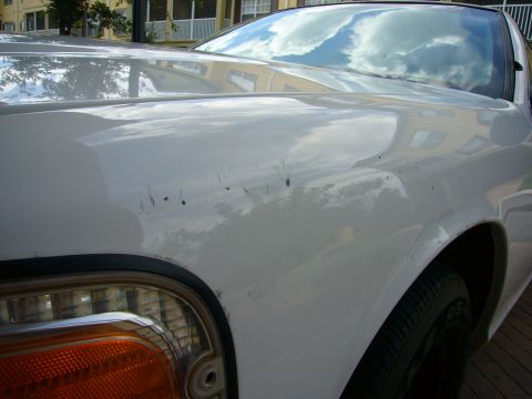 2001 Ford Crown Victoria - Front fender and headlight of a white car with visible scratches.