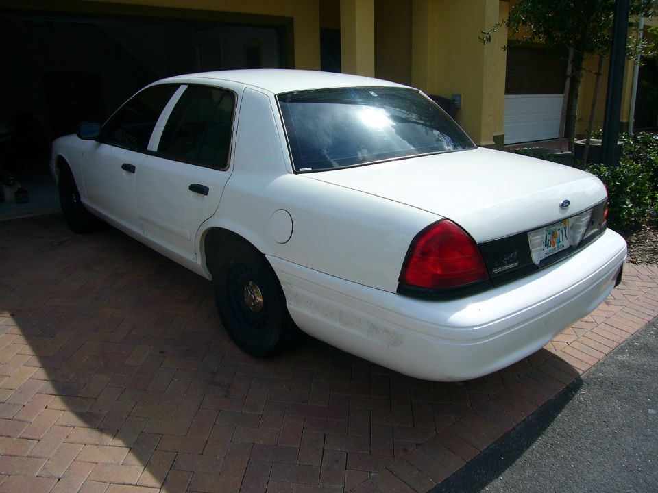 White 2001 Ford Crown Victoria sedan parked on brick driveway, rear quarter view