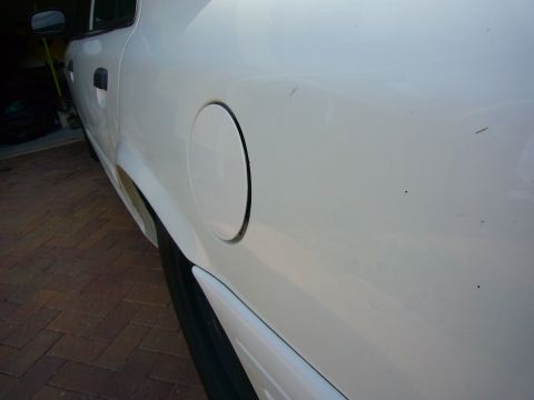 2001 Ford Crown Victoria - The side profile of a white 2001 Ford Crown Victoria, highlighting the fuel door and rear quarter panel.