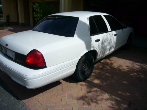 2001 Ford Crown Victoria - A white 2001 Ford Crown Victoria sedan is parked in a driveway, viewed from the rear three-quarter angle.