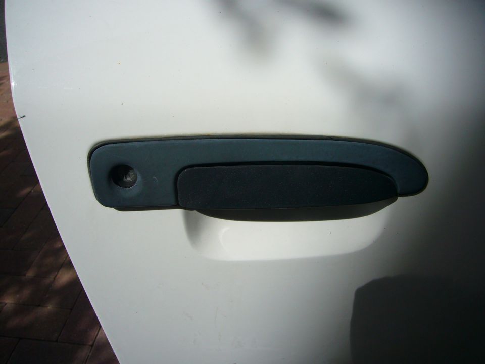 Close-up of a white car door with a black door handle and keyhole