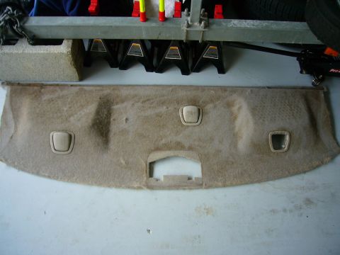 2001 Ford Crown Victoria - A tan car interior trim panel with three light beige plastic clips is laid out on a garage floor.