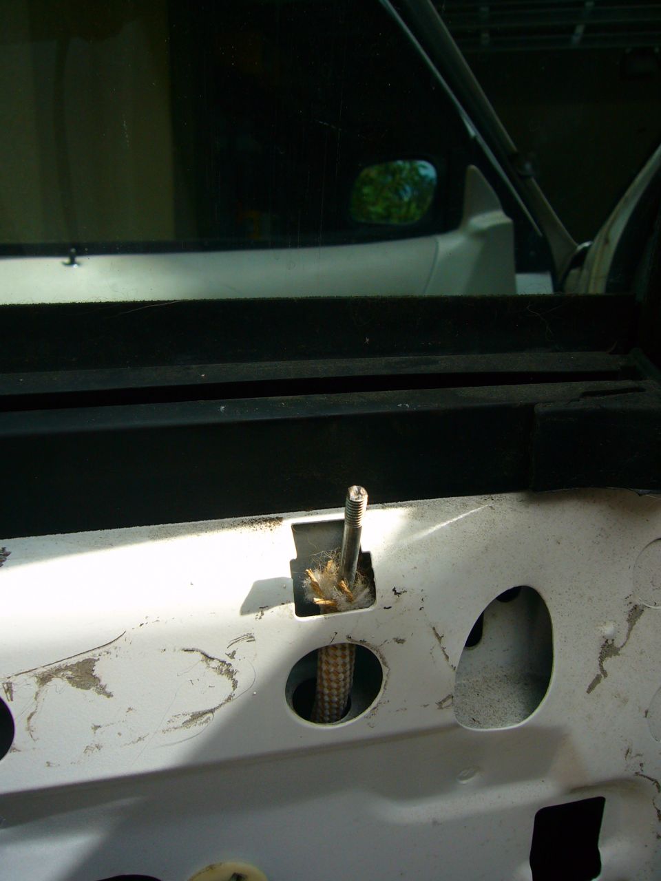 Close-up of a car's interior door panel showing a bolt and cable mechanism
