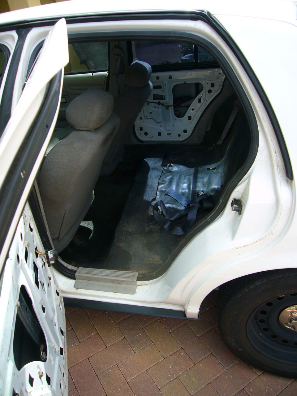 White 2001 Ford Crown Victoria interior with rear doors open, showing stripped door panels and seats