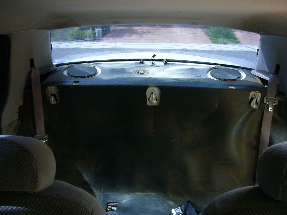 Back seat and trunk area of a car, showing speakers and seatbelts