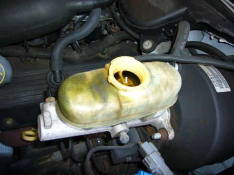 2001 Ford Crown Victoria - The brake fluid reservoir in a 2001 Ford Crown Victoria shows a visible fluid level with the yellow cap open.