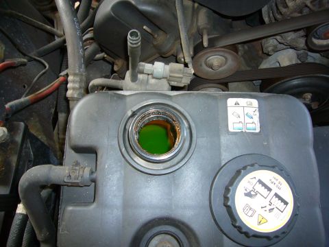 2001 Ford Crown Victoria - Close-up of a vehicle's engine bay, focusing on the coolant reservoir and its associated hoses and components.