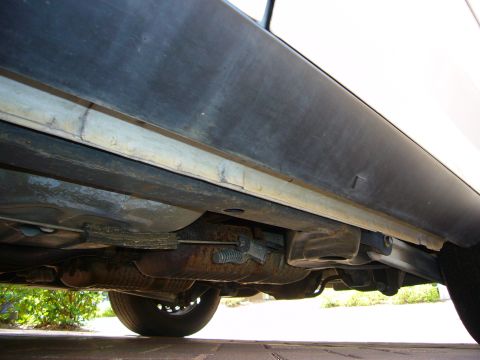 2001 Ford Crown Victoria - A low-angle shot reveals the underside of a vehicle, focusing on the exhaust components and structural elements.