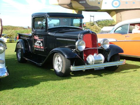 1988 Ford Sport - Black 1930s Ford hot rod pickup truck with custom wheels and "Eighty-Eight Parts" lettering on the door.