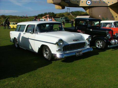 1988 Ford Sport - A classic white 1955 Chevrolet Nomad station wagon is displayed at an outdoor event with other vintage vehicles.