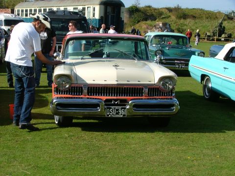 1988 Ford Sport - A man polishes a classic Mercury at an outdoor car show with other vintage vehicles present.