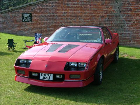 1988 Ford Sport - This red sports coupe features distinctive hood scoops and a front license plate. The vehicle appears to be from the late 1980s.