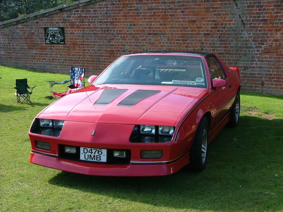 Red sports coupe with hood scoops and a license plate reading D476 UMB