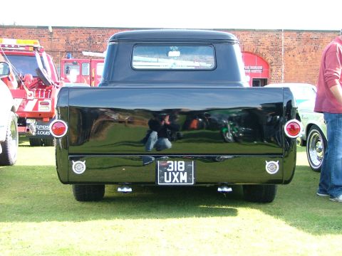 1988 Ford Sport - A black pickup truck is viewed from the rear, parked on grass with other vehicles nearby.