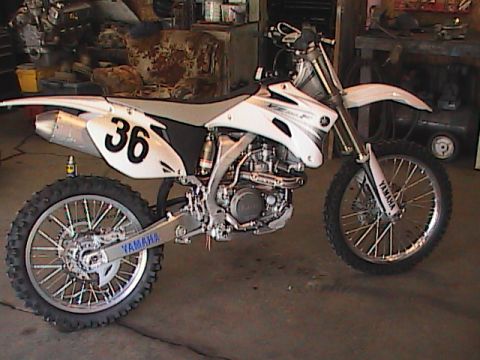 2007 Yamaha YZ450F - A white Yamaha dirt bike is parked inside a garage, showing its engine and rear wheel.