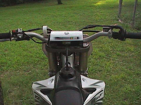2007 Yamaha YZ450F - Close-up view of motorcycle handlebars and fuel tank with grass in the background.