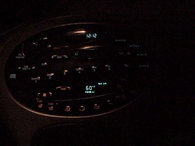 Car dashboard with digital clock showing 12:12 and temperature display showing 60 degrees