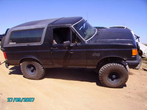 1990 Ford Bronco - Side view of a black 1990 Ford Bronco with aftermarket off-road tires.
