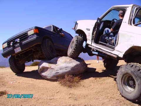 1990 Ford Bronco - Two SUVs navigate a rocky trail, demonstrating their off-road capabilities.