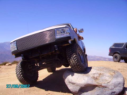 1990 Ford Bronco - A white Ford Bronco is positioned on a large rock with another Bronco in the background.