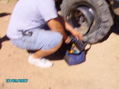 1990 Ford Bronco - A person is seen working on a large tire with a tool bag nearby.