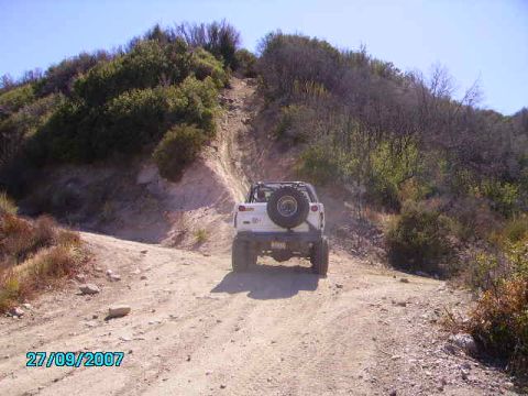 1990 Ford Bronco - White 1990 Ford Bronco navigates a challenging dirt trail on a sunny day.