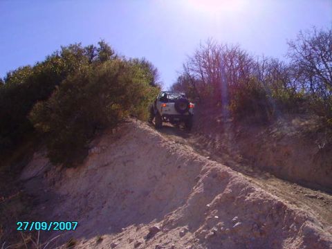 1990 Ford Bronco - A white SUV navigates a dusty trail, with a spare tire mounted on the back.