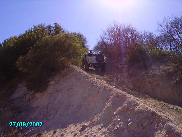 White SUV with spare tire on rear driving on a dirt trail