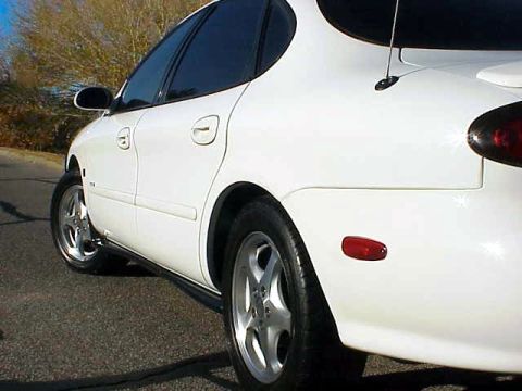 1999 Ford Taurus - This white 1999 Ford Taurus is captured from a 3/4 front angle, highlighting its side and rear quarter panel.