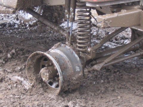 1989 Ford Bronco - The vehicle's wheel is deep in mud, showing the suspension system and the muddy terrain.