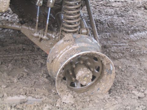 1989 Ford Bronco - A vehicle's wheel and suspension are submerged in thick mud, indicating it is stuck.