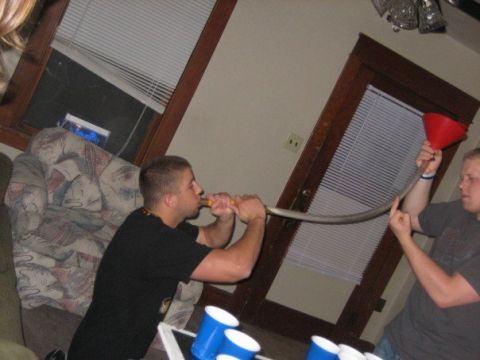 1996 Ford Bronco - Two men are using a funnel and tube to pour liquid into a cup.