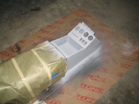 1989 Ford Bronco - A vehicle's center console part is being prepped for painting, laid out on cardboard.