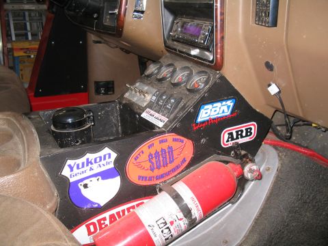 1989 Ford Bronco - The center console features auxiliary gauges, switches, and various off-road stickers, along with a mounted fire extinguisher.