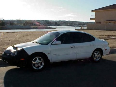 1999 Ford Taurus - This 1999 Ford Taurus is captured from the side, a black car bra on the front end.