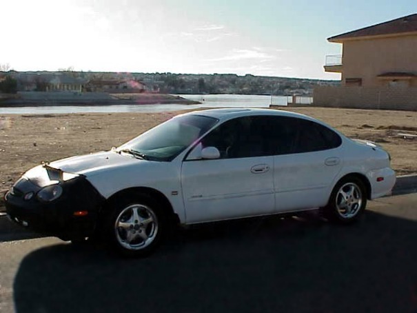 White 1999 Ford Taurus sedan with a black car bra, side view