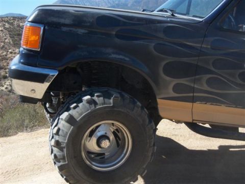 1995 Ford Bronco - This Ford Bronco features flame decals and large off-road tires, suggesting it's modified for off-road use.