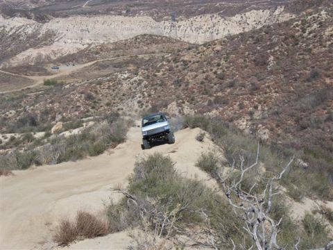 1995 Ford Bronco - A white 1995 Ford Bronco navigates a narrow dirt path on a steep, arid hillside.