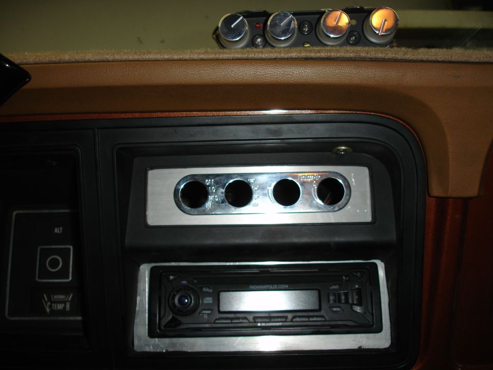 Aftermarket car stereo and four auxiliary switches installed in a dashboard