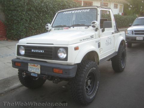 1987 Suzuki Samurai - This 1987 Suzuki Samurai features off-road tires and various decals, parked on a street.