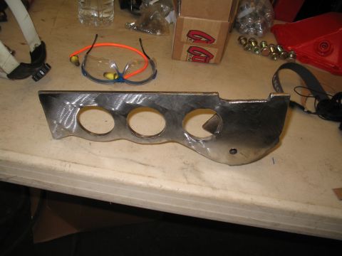 1989 Ford Bronco - A metal bracket with multiple circular cutouts is shown on a workbench, with safety glasses and other items in the background.