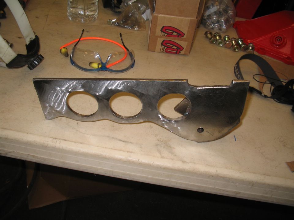 Metal bracket with three circular cutouts and a triangular cutout, on a workbench
