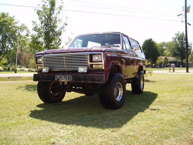 Maroon lifted Ford Bronco front three-quarter on grass