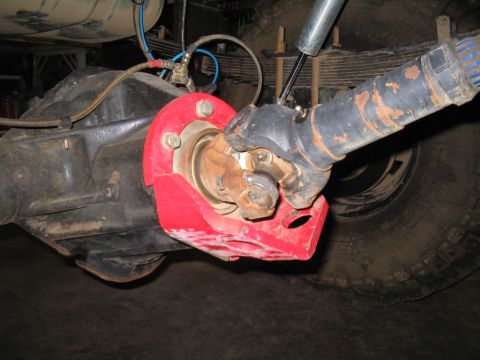 1989 Ford Bronco - Close-up of a vehicle's rear differential housing with a red pinion guard and driveshaft yoke.