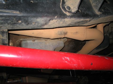 1989 Ford Bronco - A close-up view of the exhaust system and undercarriage components of a vehicle.