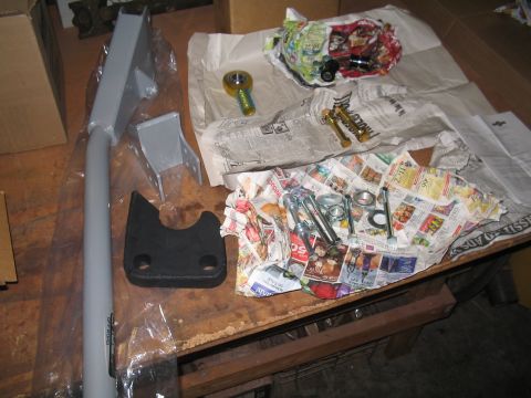 1989 Ford Bronco - Various suspension components and hardware are laid out on a table, wrapped in newspaper.