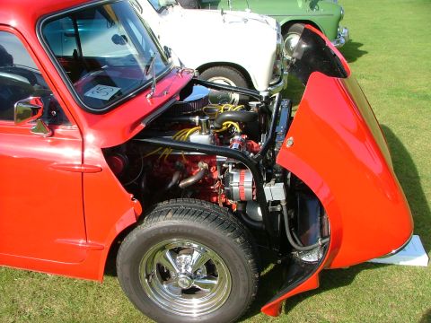 1988 Ford Sport - Engine bay of a red classic car, with other vehicles visible behind it.