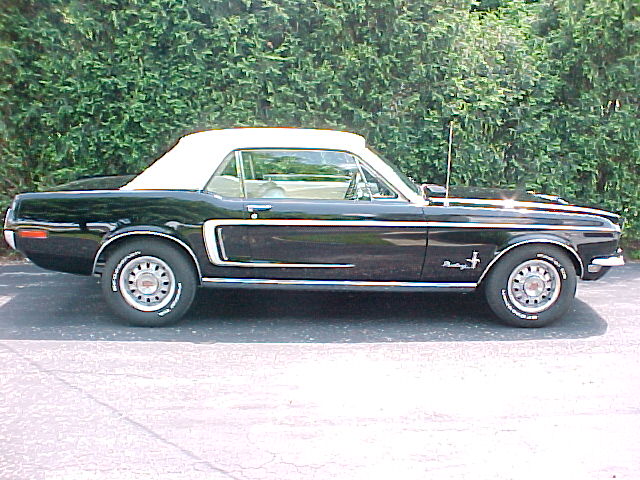 Black 1969 Ford Mustang convertible with white top parked outside