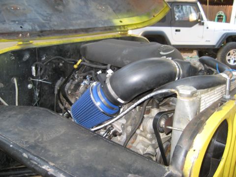 1966 Jeep CJ5 - The engine bay of a yellow Jeep shows an aftermarket air intake system and a Vortec engine cover. A white Jeep is visible in the background.